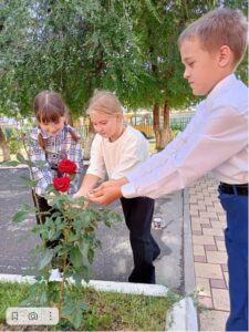 Ребята начальной школы поливают розы